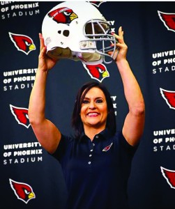 Jen Welter holds an Arizona Cardinals helmet aloft at a press conference. Welter is the first female coach in any capacity in the history of the NFL. (Photo courtesy - Arizona Cardinals)